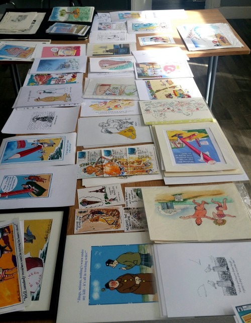 The show featured new cartoons by dozens of cartoonists on the theme of seaside postcards, here about to be hung, as well as a small exhibition of prosecuted cards by Donald McGill, king of the saucy postcard